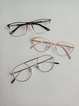 A flat lay of three stylish eyeglasses on a white surface, showcasing fashion eyewear trends.