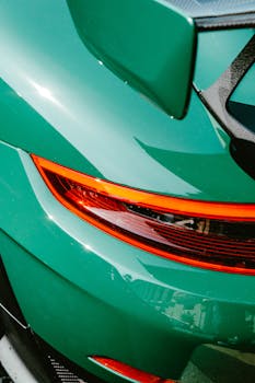 A detailed view of a shiny green sports car's elegant tail light and aerodynamic design.