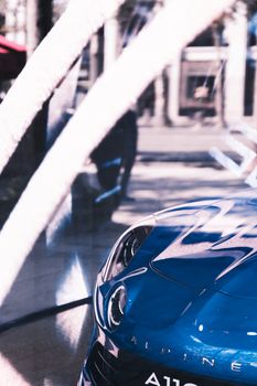 Close-up of a sleek blue car with reflective surface outdoors, capturing modern aesthetics and transport design.