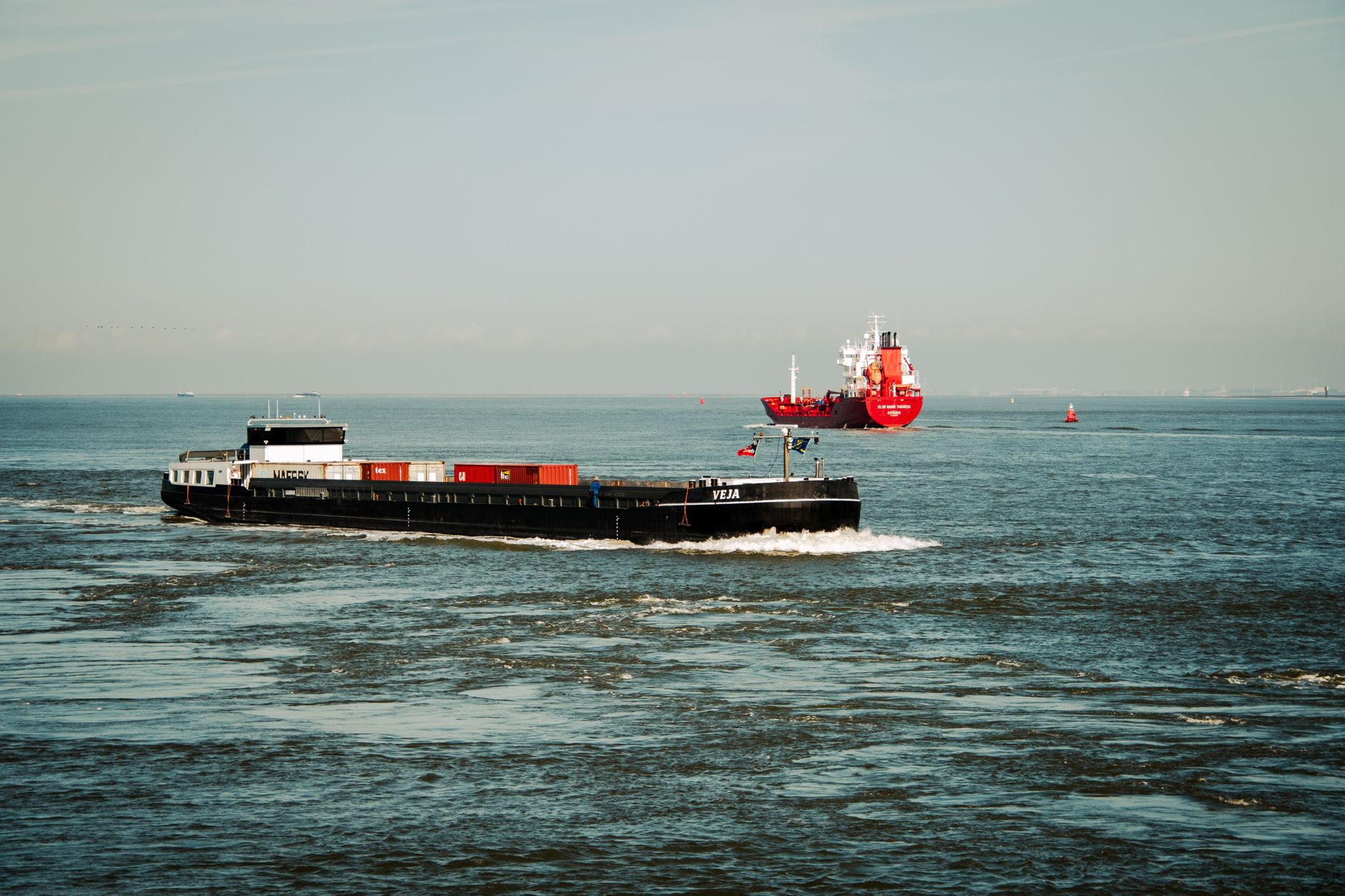 Container ships navigating ocean waters under a clear sky, showcasing maritime transport.