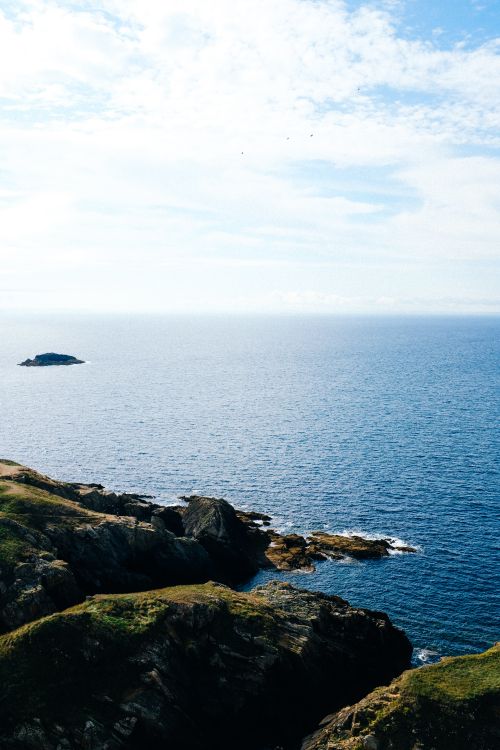 Free A breathtaking view of rocky cliffs by a calm ocean under a clear sky. Stock Photo