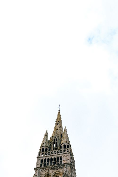 Free Gothic architecture cathedral tower captured from a low angle with a bright white sky. Stock Photo
