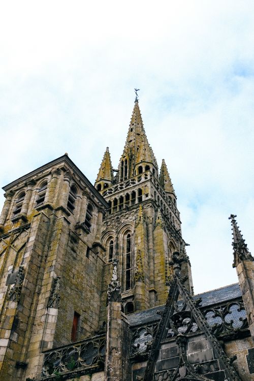 Free Low angle view of a historic Gothic cathedral exterior against a white sky. Stock Photo