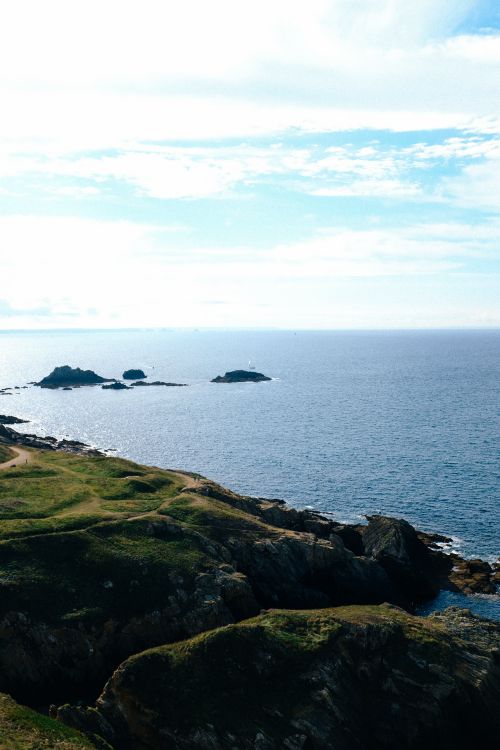 Free Peaceful coastal view with rocky cliffs and serene ocean under a blue sky. Stock Photo
