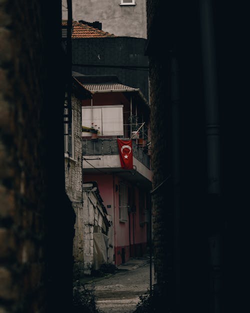 Free Narrow passage between aged shabby brick houses in Turkish old town with Turkish flag on wall Stock Photo