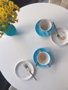 An Empty Ceramic Cups and Plates on the Table Near the Flower Vase