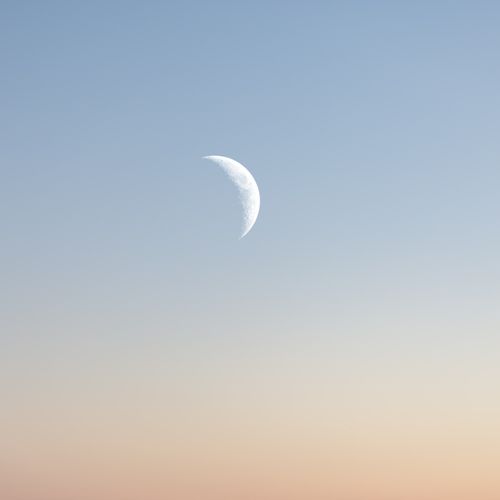 Free A crescent moon set against a tranquil sunset sky gradient, capturing a peaceful evening scene. Stock Photo
