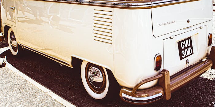 Classic white Volkswagen van parked on pavement. Vintage aesthetic with close-up details.
