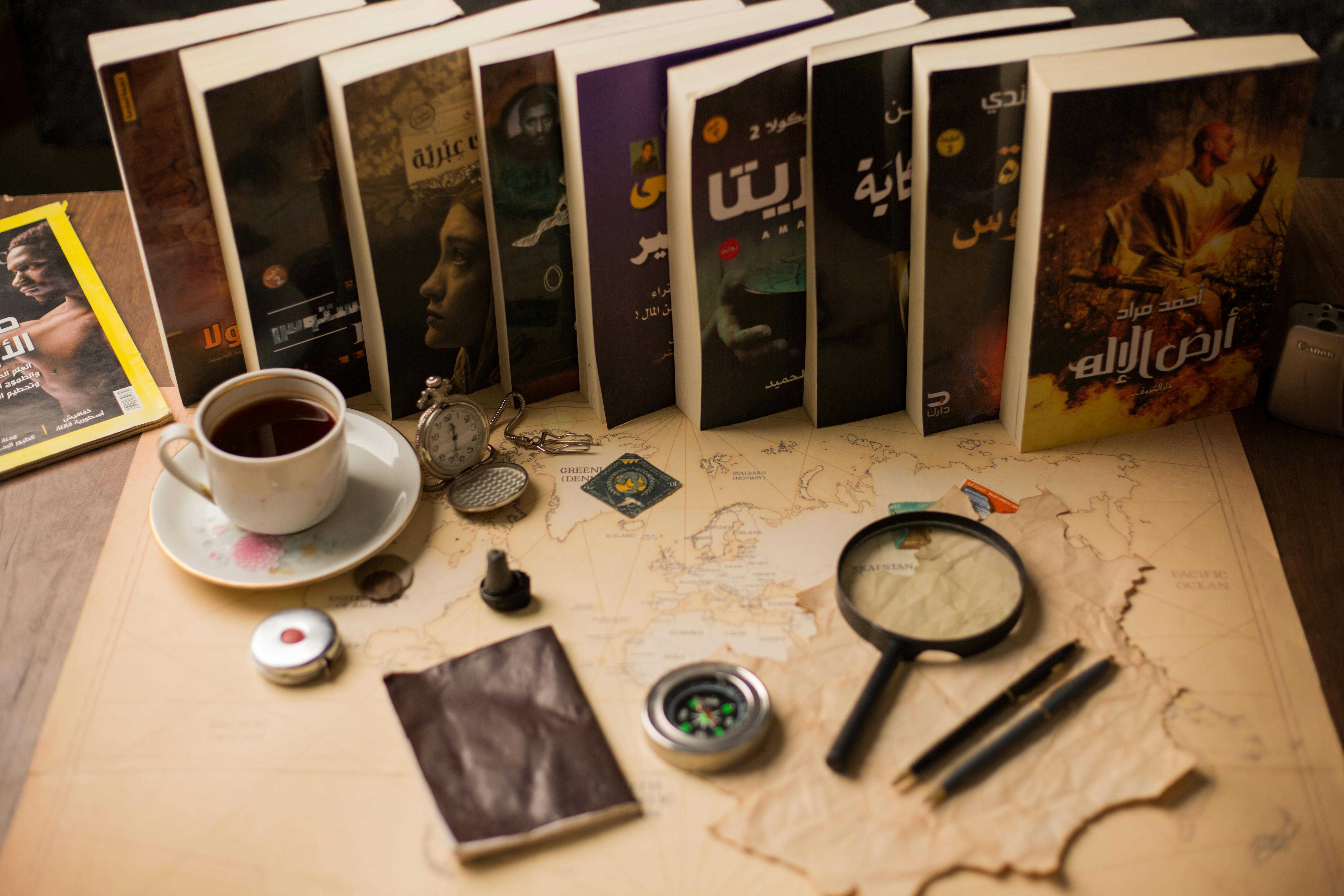 Warm desk scene featuring books, a map, and vintage items like a compass and magnifying glass.