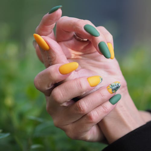 Free Person's Fingernails with Green and Yellow Nail Polish Stock Photo