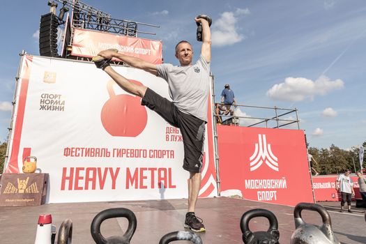 Man displaying strength at a kettlebell competition outdoor festival.