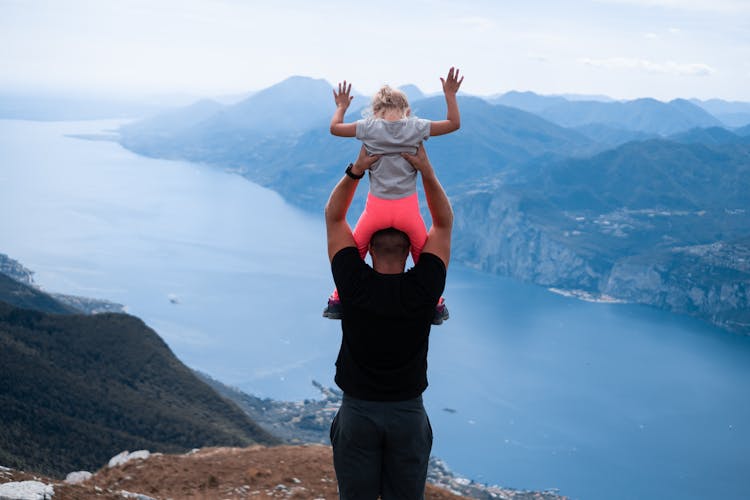 Father Picking Up Daughter On Mountain Peak