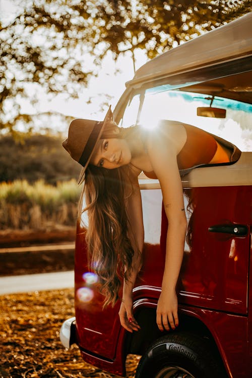 A Woman Wearing a Hat while Leaning Out of Car