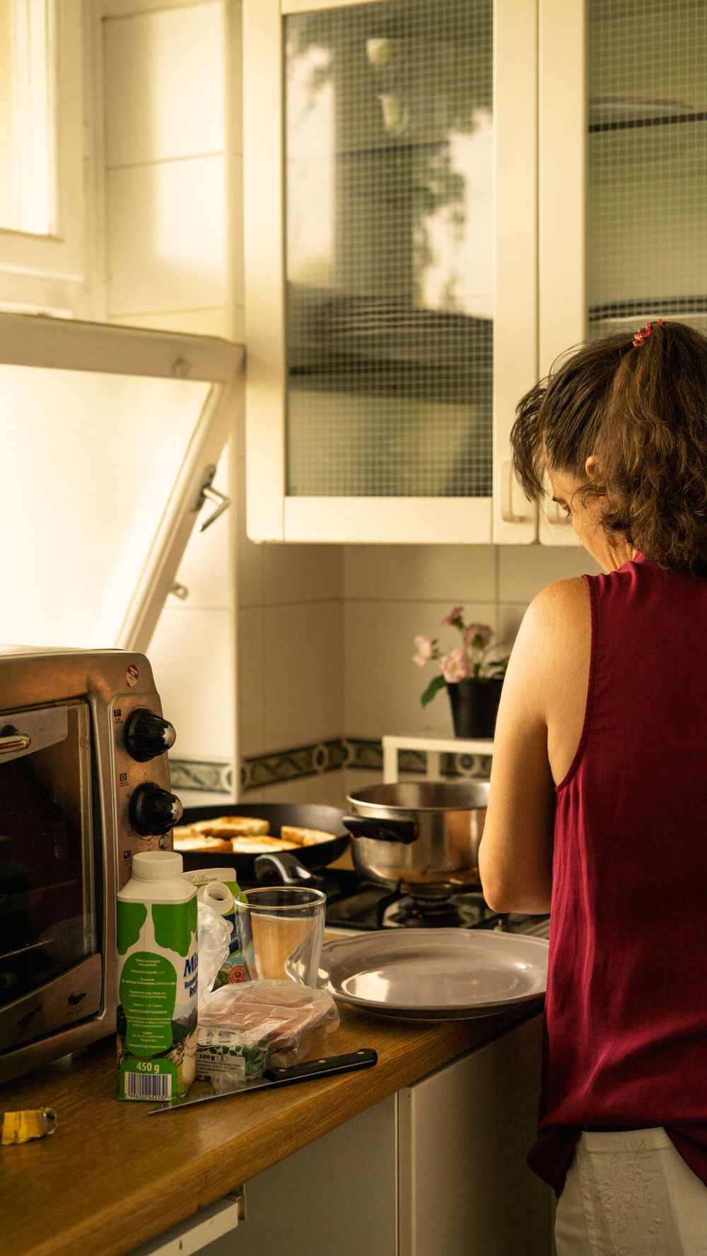 Mulher cozinhando em casa, vista traseira, luz natural no balcão da cozinha