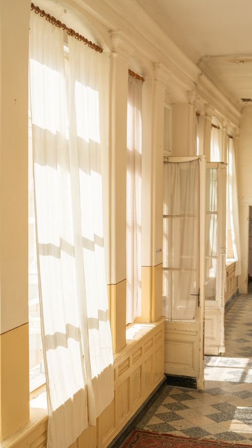Free Bright hallway with flowing white curtains and vintage design elements, showcasing natural light. Stock Photo