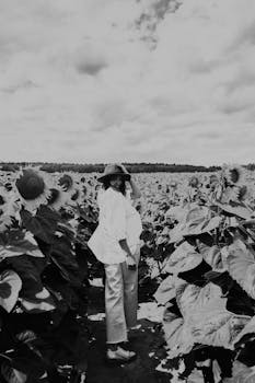 A woman stands in a vast sunflower field captured in black and white, creating a timeless feel.