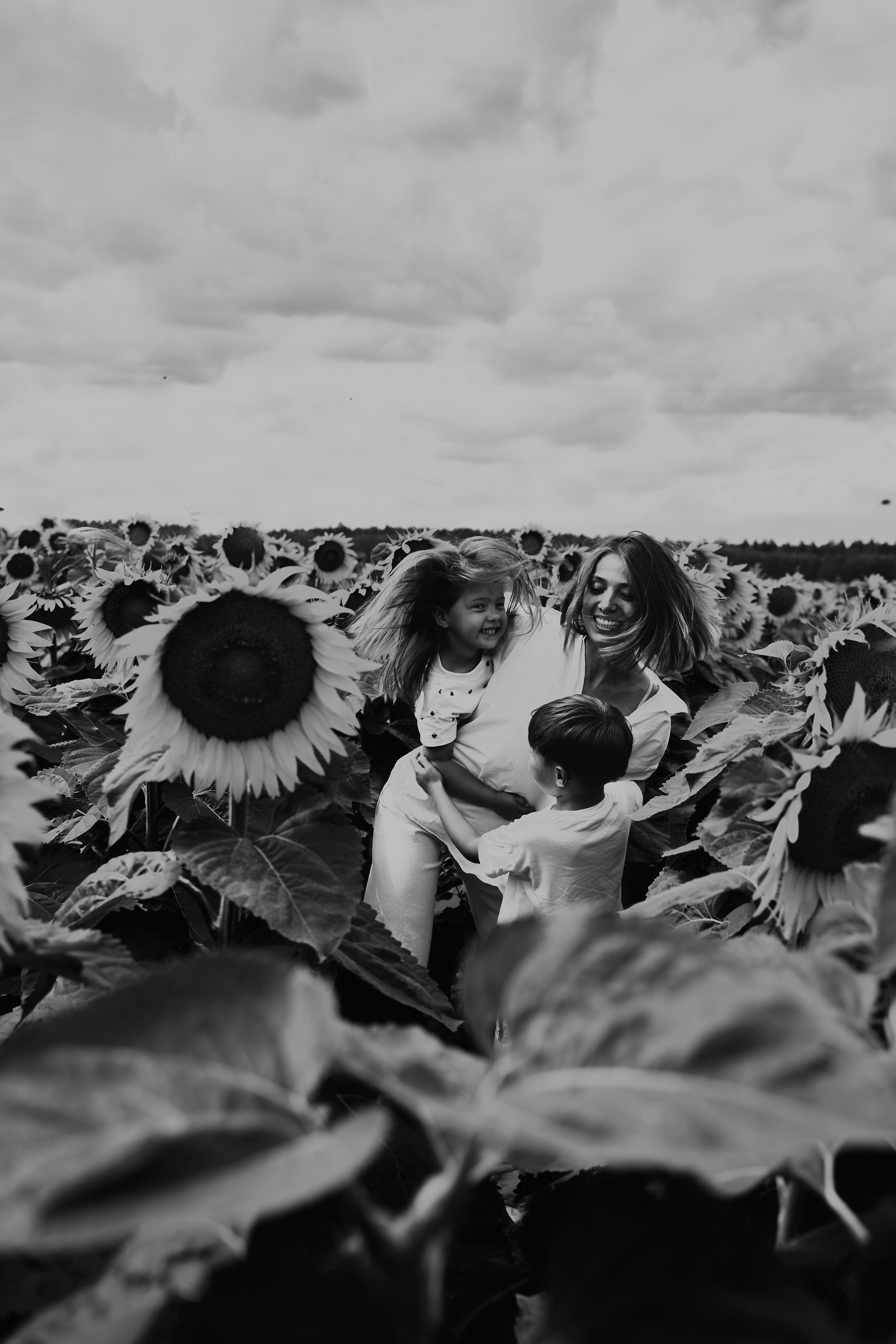 grayscale photo of woman and girl sitting on sunflower field