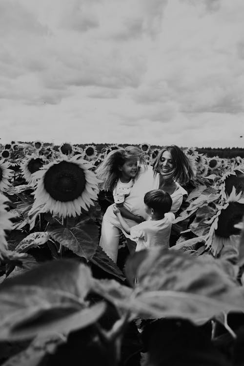 Grayscale Photo of Woman and Girl Sitting on Sunflower Field