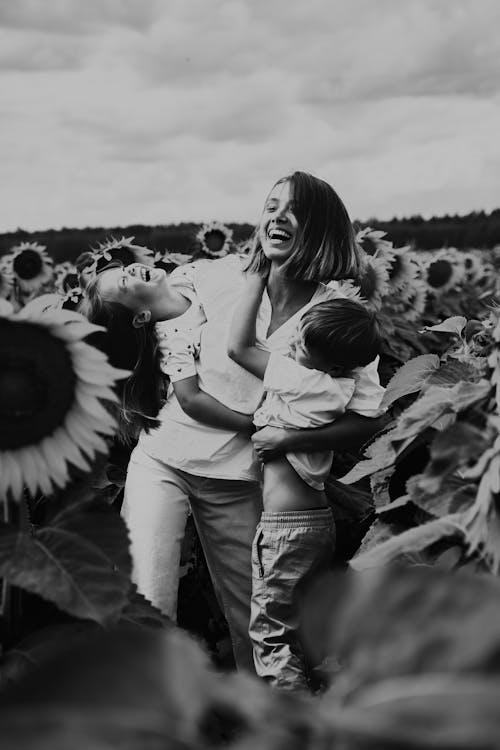 A Woman Carrying Her Children on a Sunflower Field