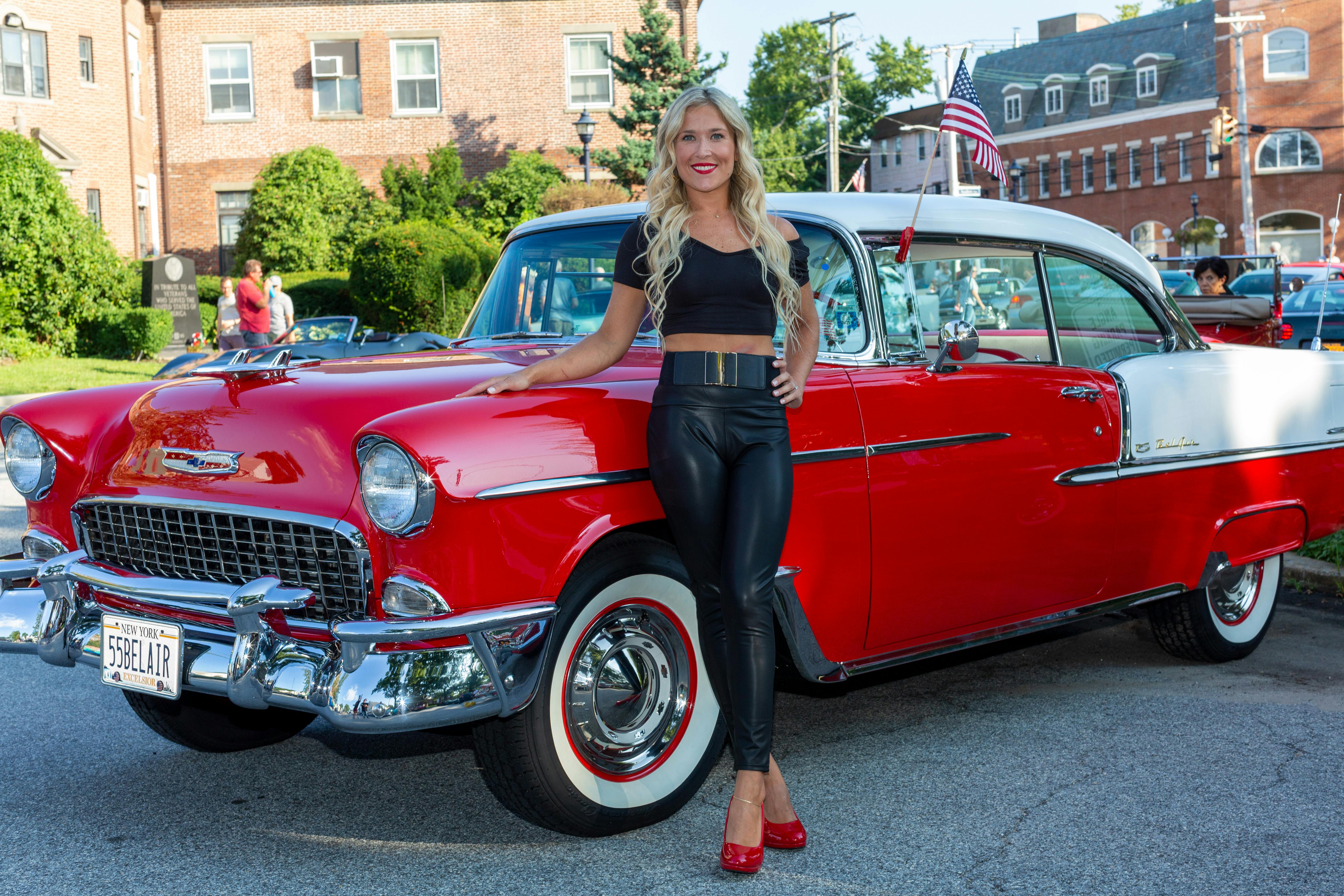 A Woman Smiling while Leaning on the Red Car · Free Stock Photo