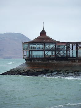 A pavilion by the sea with a mountainous backdrop, ideal for landscape photography.