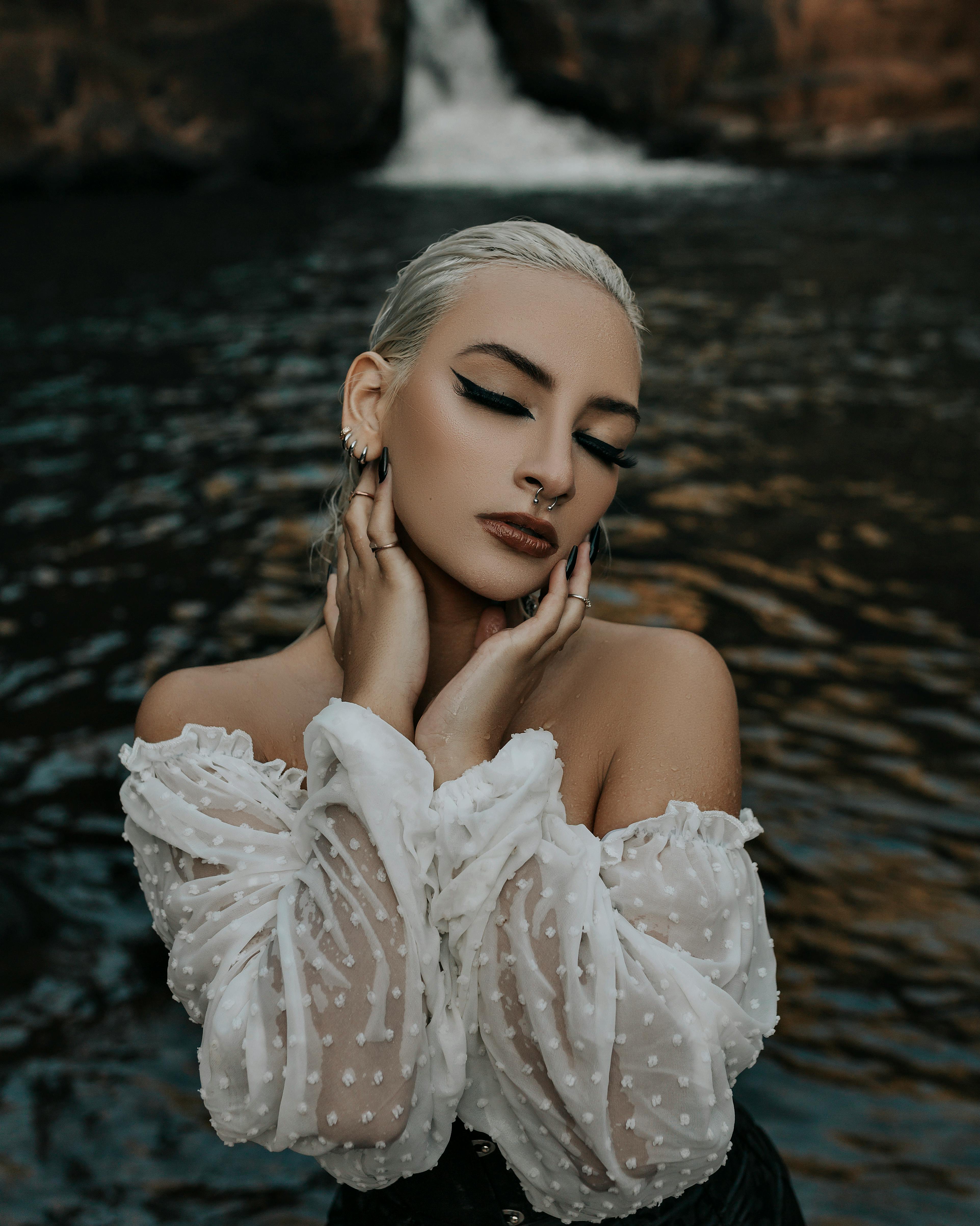 一位闭着眼睛的女性时尚肖像，以瀑布为背景，展示了时尚和美丽