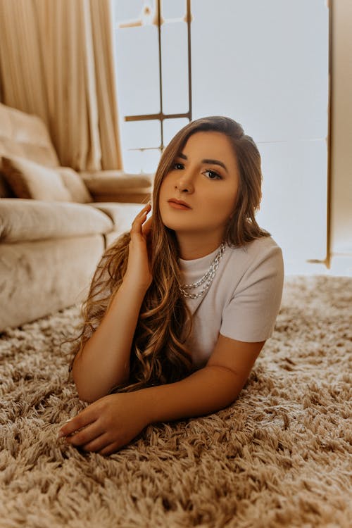 Woman in White T-shirt Lying on Brown Carpet