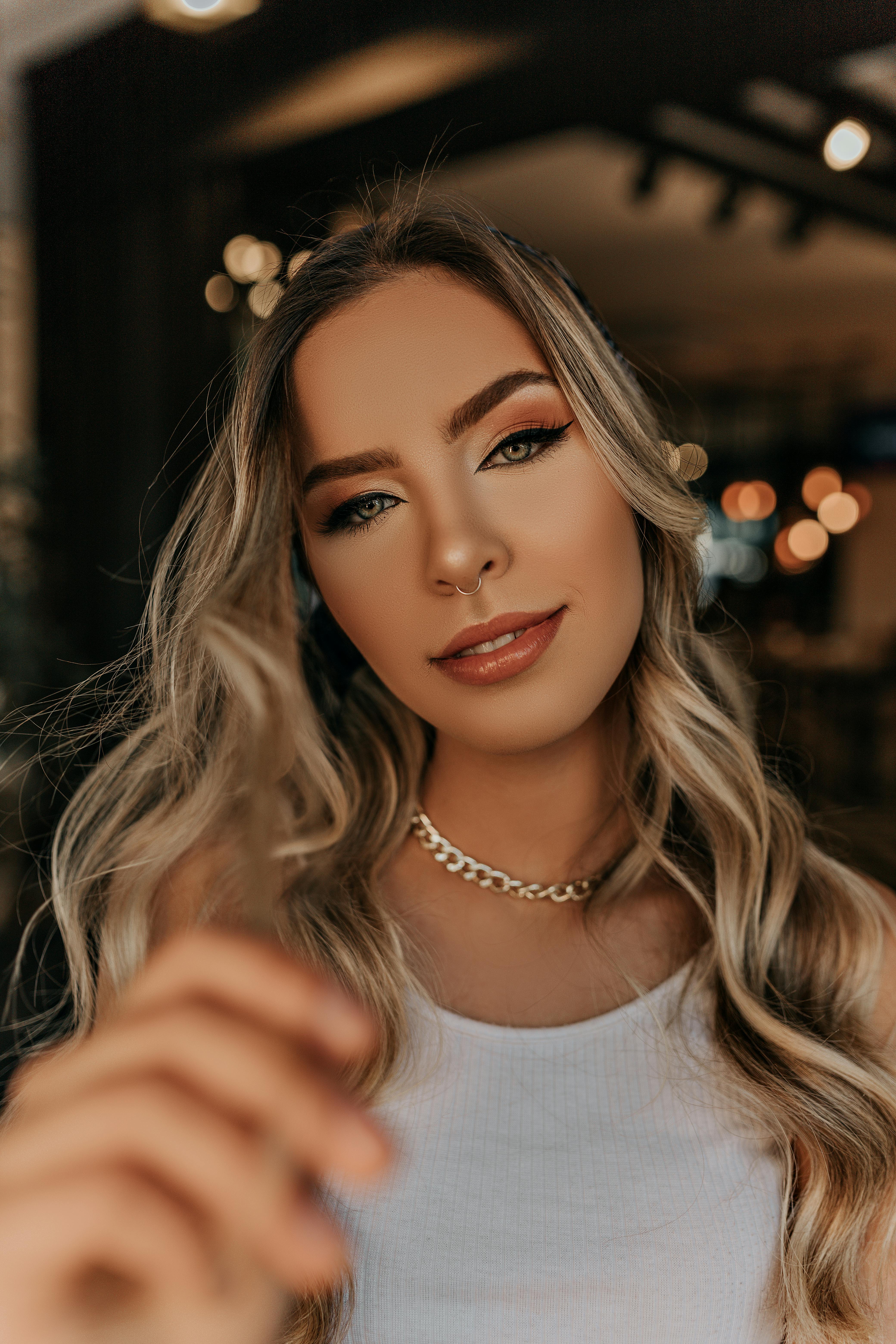 室内一位金发女子的优雅肖像，一头卷发，戴着隔膜环，展现了现代时尚