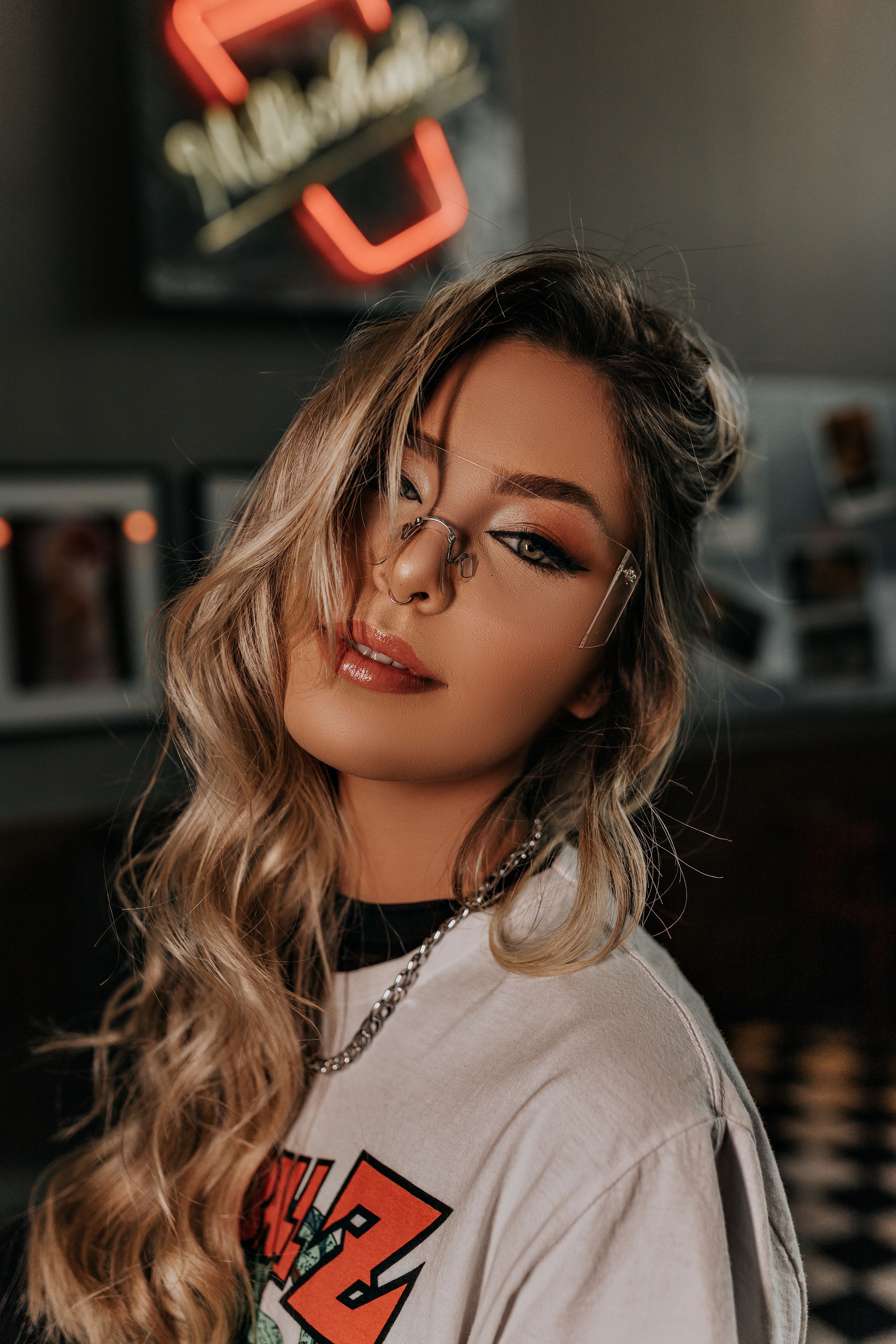 Retrato de uma mulher fashionista usando óculos e um traje moderno em ambiente interno.