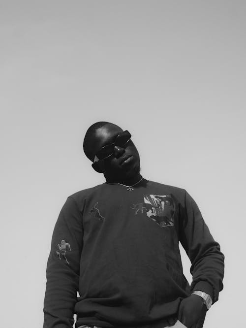 Grayscale Photo of a Man with Sunglasses Posing with His Hand in His Pocket