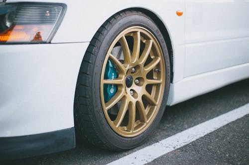 Close-Up Photo of Gold Rims of a White Car