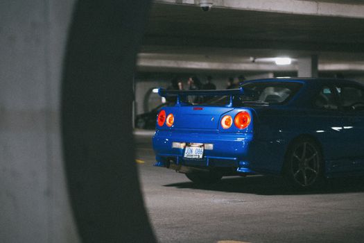 A blue Nissan Skyline GT-R parked in an underground garage, showcasing its sport design and tail lights.