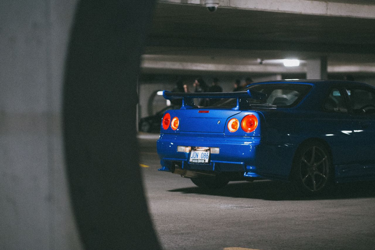 a blue nissan skyline gt r parked in an underground garage showcasing