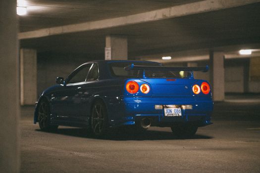 Blue Nissan Skyline GT-R parked in an empty underground garage, showcasing its sporty design.