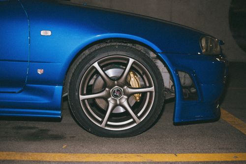 Free Close-up of a blue Nissan GT-R's front wheel in a parking garage at night. Stock Photo