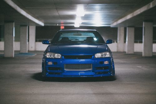 Free Front view of a shiny blue classic car parked in a dimly lit urban parking garage. Stock Photo