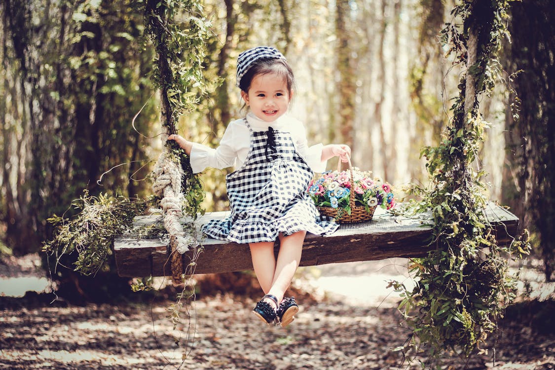Free Girl in Black and White Overall Skirt Holding Basket With Petaled Flowers Stock Photo