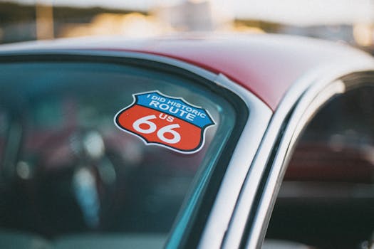 Close-up of a Route 66 decal on a classic car's windshield, symbolizing travel and adventure.