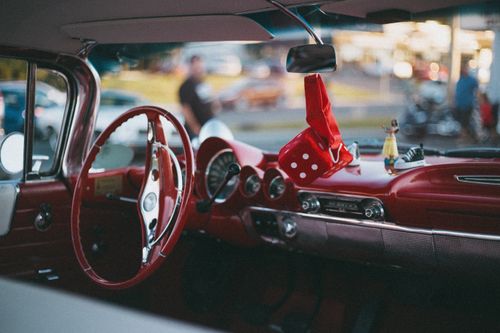 Free Stylish red vintage car interior showcasing a classic steering wheel and dashboard with fun dice accessory. Stock Photo