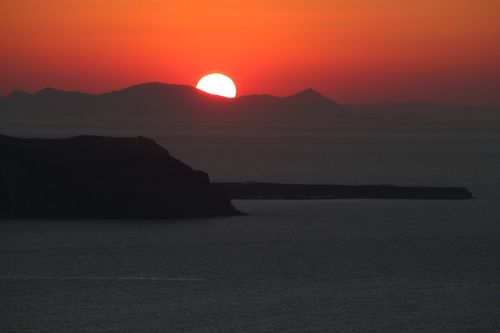 Free Stunning sunset view over the Aegean Sea from Thera, Greece, featuring vivid colors and a serene seascape. Stock Photo