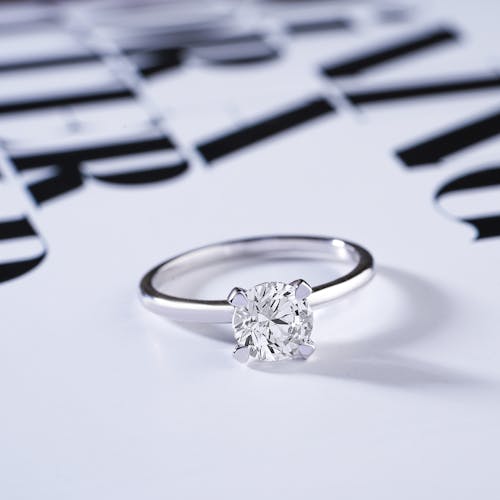 Free Close-Up Shot of a Diamond Ring on a White Surface Stock Photo