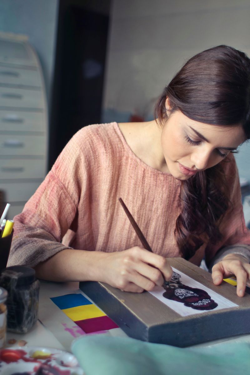 Female artist deeply engaged in painting at her creative studio workspace.