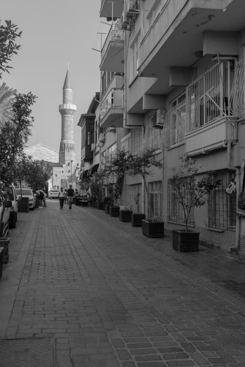 Grayscale Photo of People Walking on Sidewalk Near Buildings