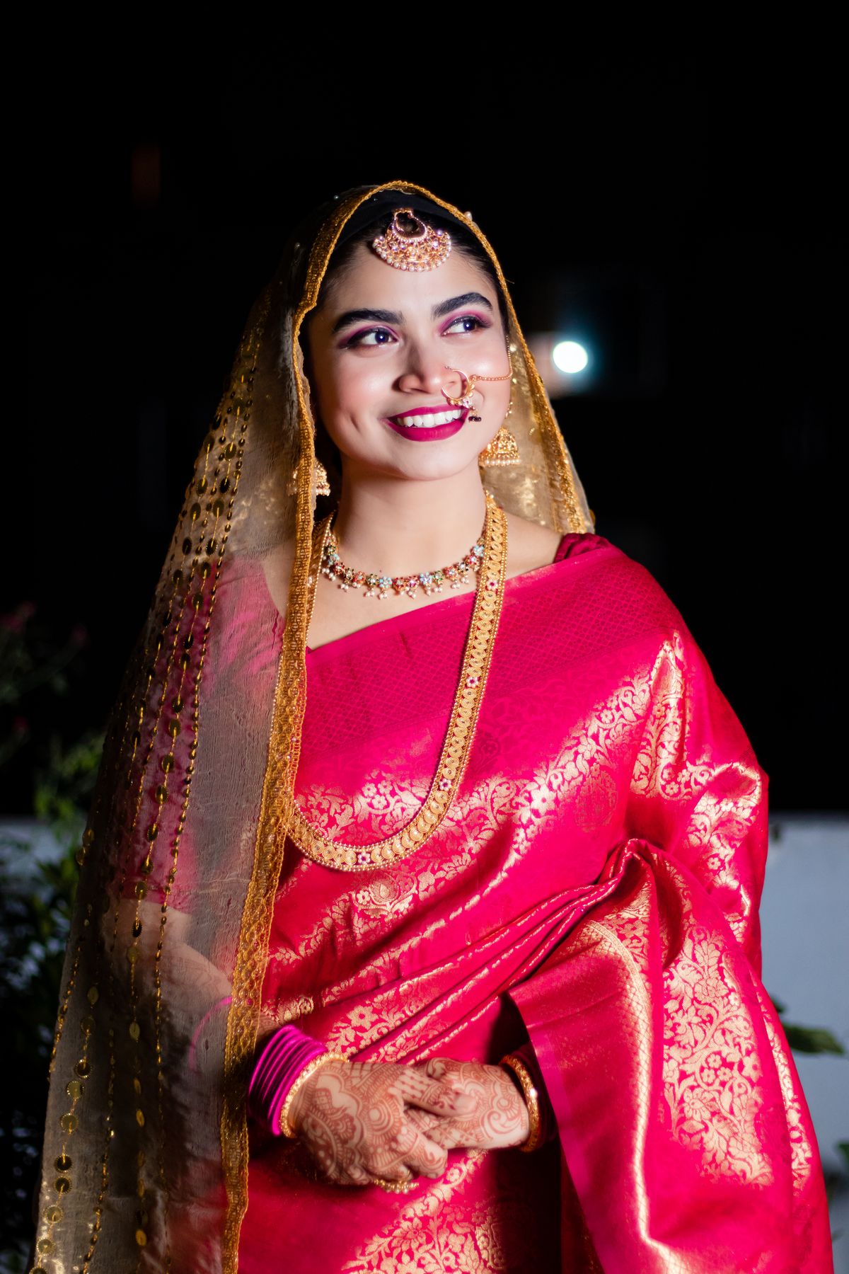 Bride in a rani-pink silk saree woven with gold zari