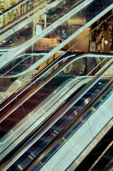 Sleek escalators with reflective glass panels in a modern indoor setting.