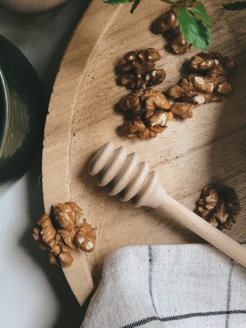 Wooden Honey Dipper Beside Walnuts