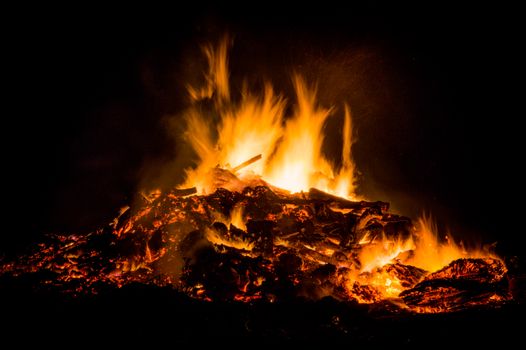 A mesmerizing campfire blaze with vibrant flames and glowing embers lighting the dark night.