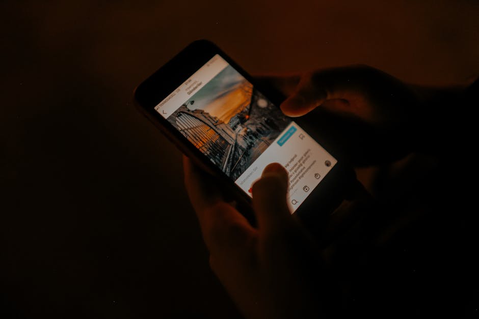 Splitwise vs Honeydue: Shared Bills Showdown Hands holding a smartphone browsing social media in low light.