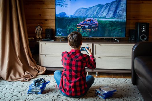 Boy in plaid shirt playing video games on console in a cozy living room setting.