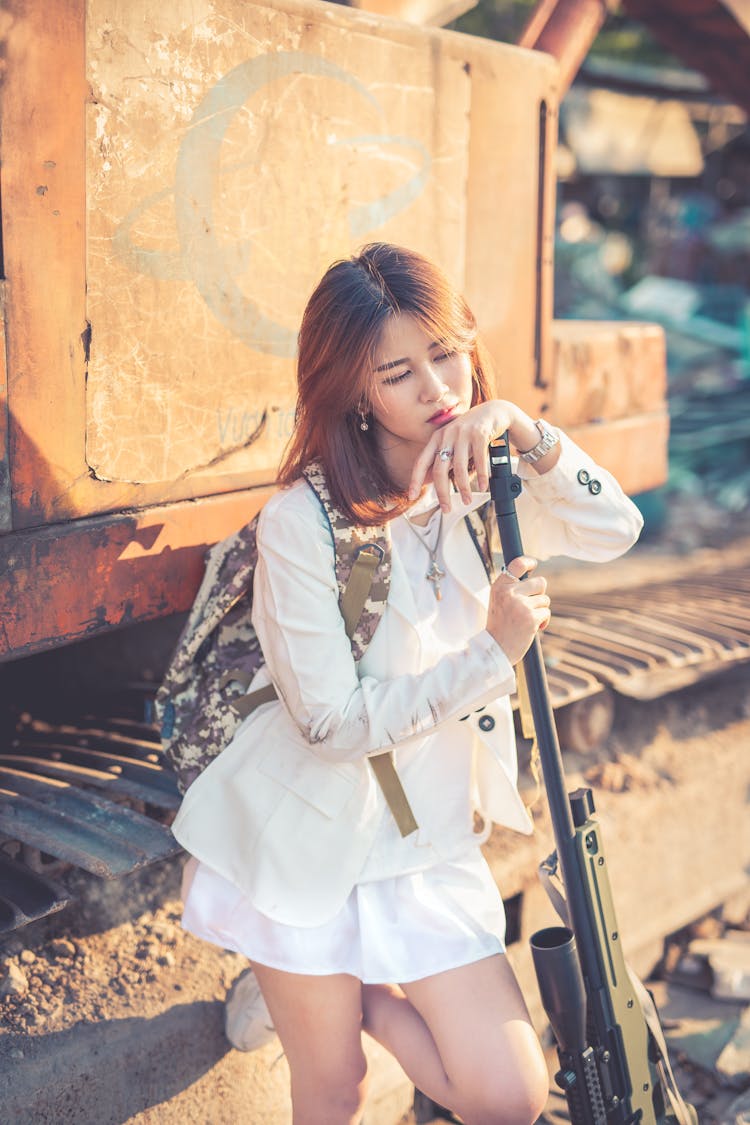 Woman Leaning On A Backhoe Holding A Sniper 